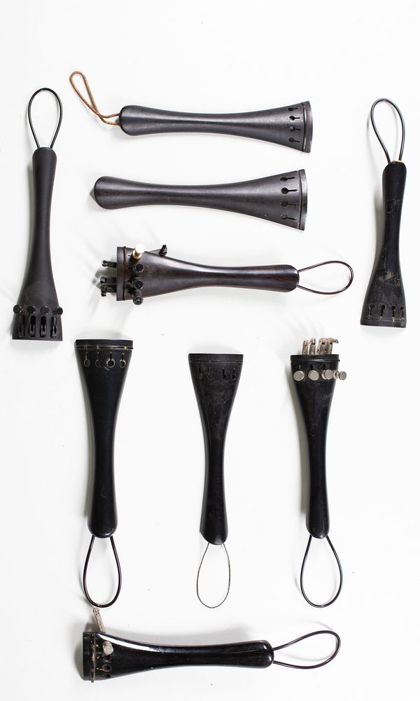 A bundle of ten cello tailpieces and two bass tailpieces
