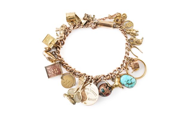 A 9CT GOLD CURB LINK BRACELET FITTED WITH TWENTY-TWO PENDANTS AND CHARMS