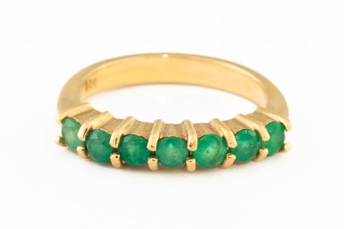 A GOLD AND EMERALD SEVEN STONE HALF HOOP RING