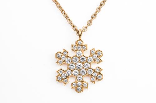 A GOLD AND DIAMOND PENDANT NECKLACE IN A HEXAGONAL SNOWFLAKE DESIGN