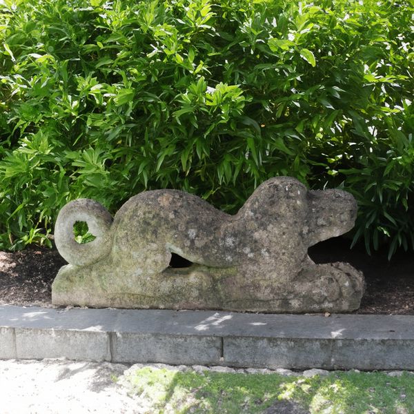 AN UNUSUAL CARVED STONE FIGURE OF A RECUMBENT MYTHICAL BEAST