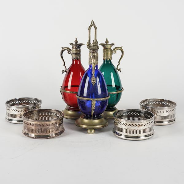 THREE VARICOLOURED GLASS DECANTERS AND STAND AND A SET OF FOUR BOTTLE COASTERS (5)