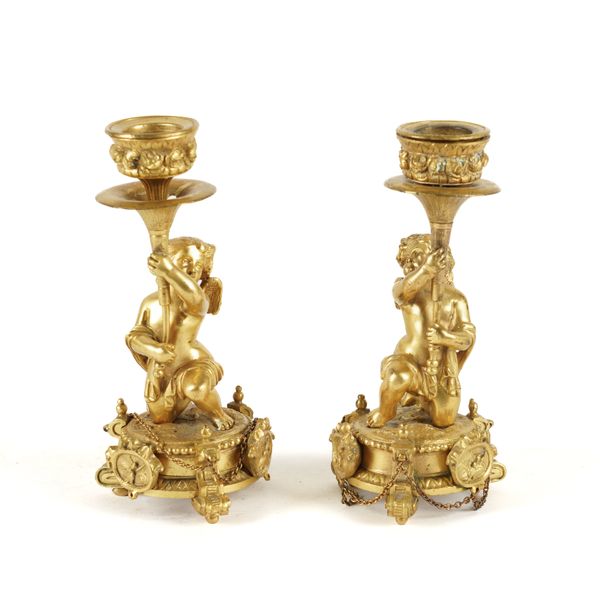 A PAIR OF FRENCH GILT-METAL KNEELING WINGED PUTTO CANDLESTICKS (2)