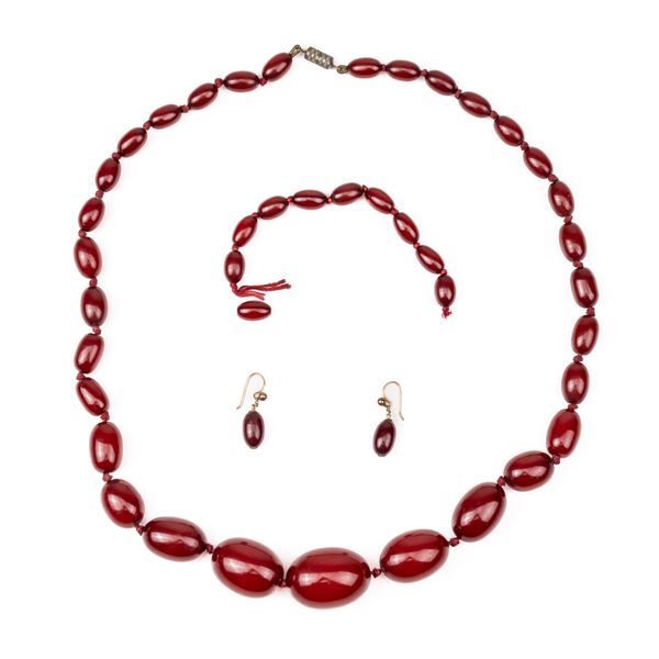 A SINGLE ROW NECKLACE OF GRADUATED CHERRY COLOURED BAKELITE BEADS SIMULATING AMBER