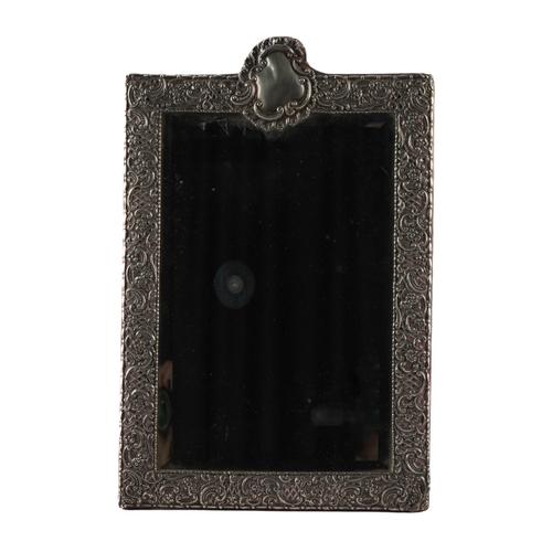 A LATE VICTORIAN SILVER MOUNTED SHAPED RECTANGULAR STRUT BACKED MIRROR