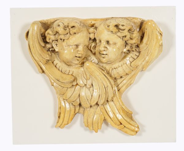 A BAROQUE STYLE CREAM PAINTED COMPOSITE WALL APPLIQUE OF TWO WINGED CHERUB HEADS