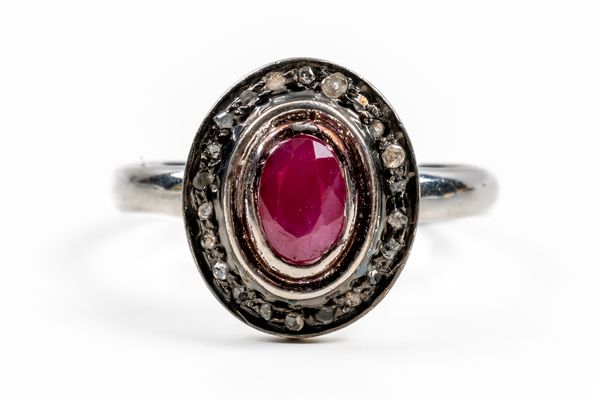 A SILVER, RUBY AND DIAMOND OVAL CLUSTER RING