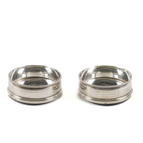 A PAIR OF SILVER BOTTLE COASTERS