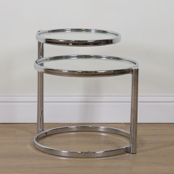 IN THE MANNER OF MILO BAUGHMAN; A CHROME AND GLASS SWIVEL DESIGN TWO TIER COCKTAIL TABLE