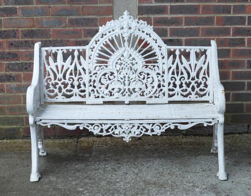 PIERCE WEXFORD; A WHITE PAINTED CAST IRON ARCHED BACK GARDEN BENCH