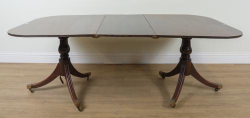 A GEORGE III STYLE MAHOGANY TWIN PILLAR EXTENDING DINING TABLE