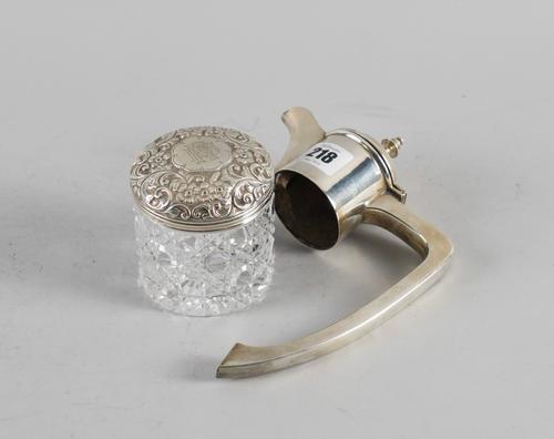 A SILVER CLARET JUG MOUNT AND A SILVER LIDDED FACETED GLASS TOILET JAR (2)