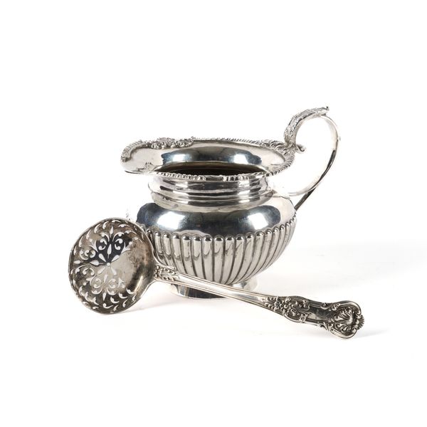 A SILVER MILK JUG AND A SILVER SUGAR SIFTING SPOON (2)