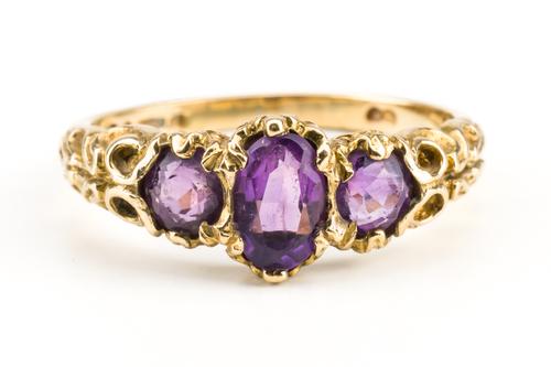 A 9CT GOLD AND AMETHYST THREE STONE RING