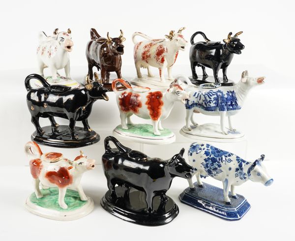 A GROUP OF NINE STAFFORDSHIRE POTTERY COW CREAMERS AND COVERS AND A DUTCH COW CREAMER (19)