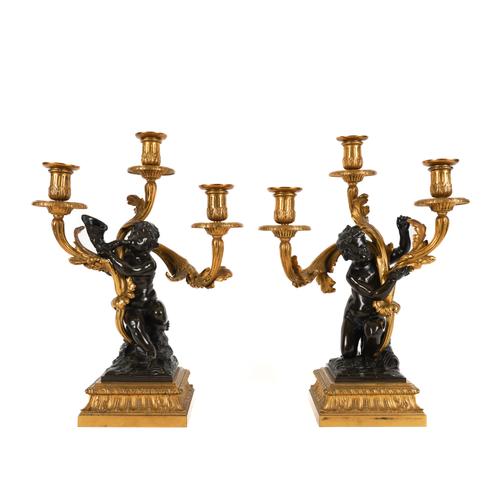 A PAIR OF NAPOLEON III ROCOCO REVIVAL ORMOLU AND PATINATED BRONZE THREE LIGHT PUTTO CANDELABRA (2)