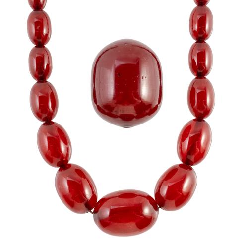A SINGLE ROW NECKLACE OF GRADUATED OVAL CHERRY COLOURED SIMULATED AMBER BEADS