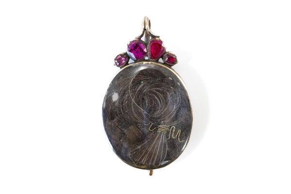 A FOIL BACKED GARNET AND GLAZED HAIR LOCKET PENDANT