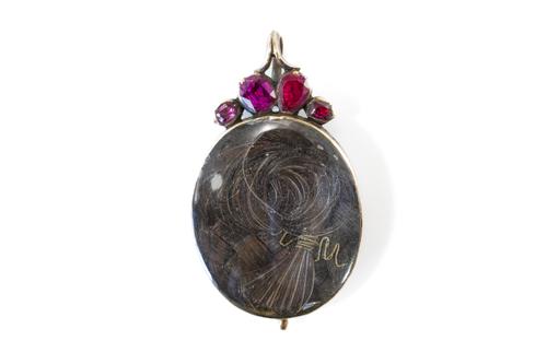 A FOIL BACKED GARNET AND GLAZED HAIR LOCKET PENDANT