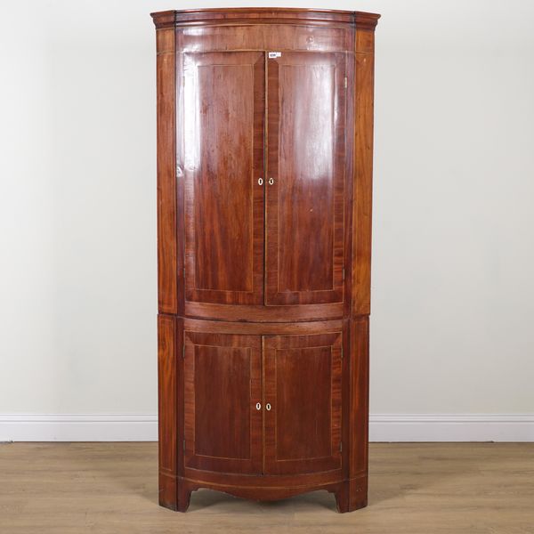 A GEORGE III BOWFRONT FLOOR STANDING DOUBLE HEIGHT CORNER CUPBOARD