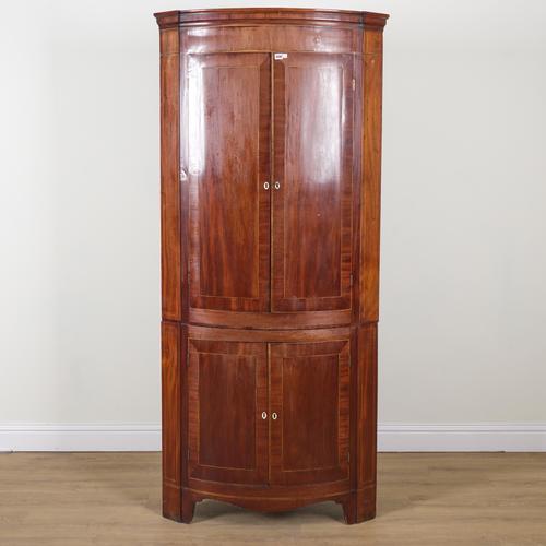 A GEORGE III BOWFRONT FLOOR STANDING DOUBLE HEIGHT CORNER CUPBOARD