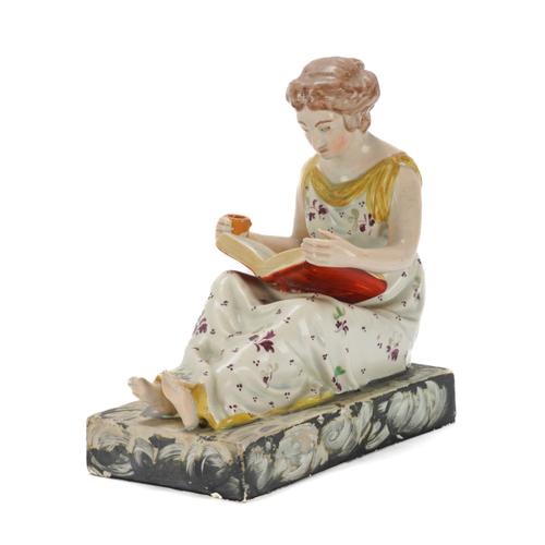 A STAFFORDSHIRE PEARLWARE FIGURE OF A GIRL READING