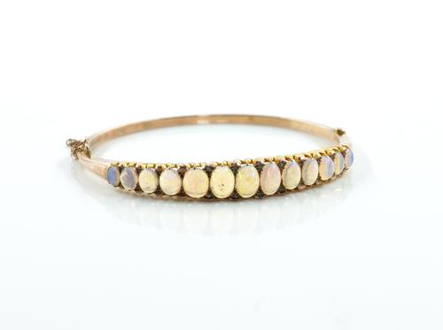 A GOLD AND OPAL OVAL HINGED BANGLE