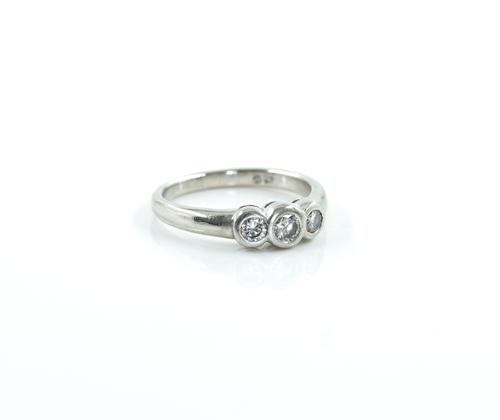 A PLATINUM AND DIAMOND THREE STONE RING