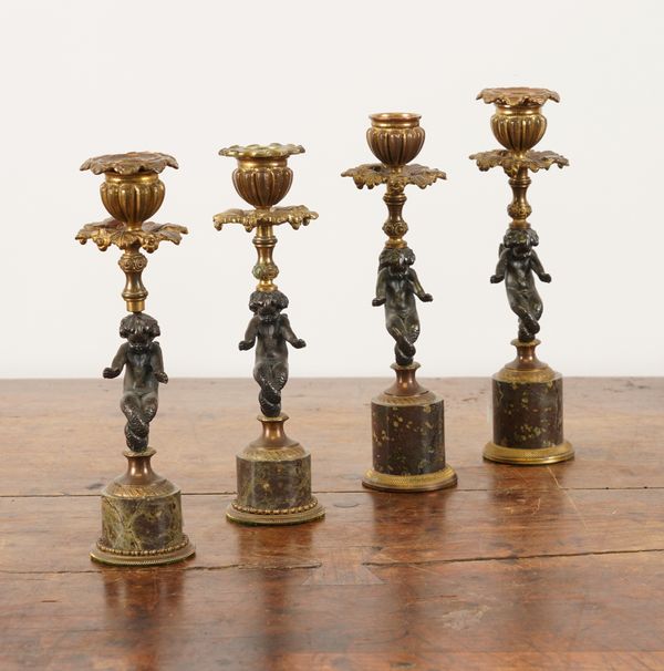 TWO PAIRS OF BRONZE AND GILT-METAL CANDLESTICKS MODELLED AS WINGED CHERUBS (4)