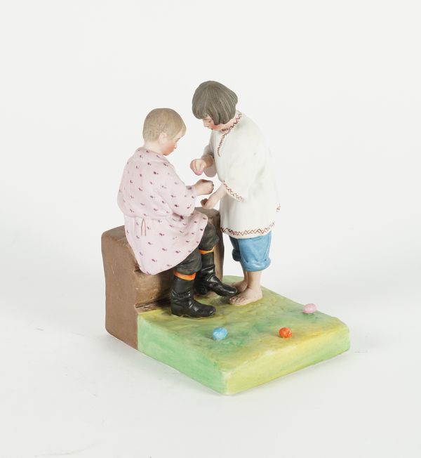 A RUSSIAN BISCUIT PORCELAIN FIGURE GROUP DEPICTING CHILDREN PLAYING WITH COLOURED EGGS