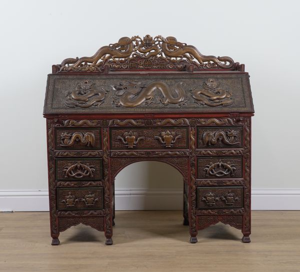 A CHINESE EXPORT CARVED HARDWOOD RED LACQUER PARCEL GILT DECORATED SEVEN DRAWER WRITING DESK