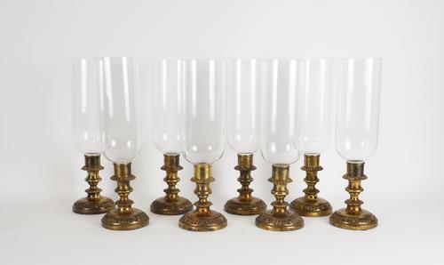 A SET OF EIGHT GILT-METAL CANDLESTICKS WITH GLASS STORM SHADES (8)