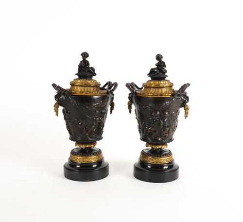 A PAIR OF FRENCH GILT MOUNTED AND PATINATED BRONZE BACCHANALIAN URNS AND COVERS AFTER CLODION (2)