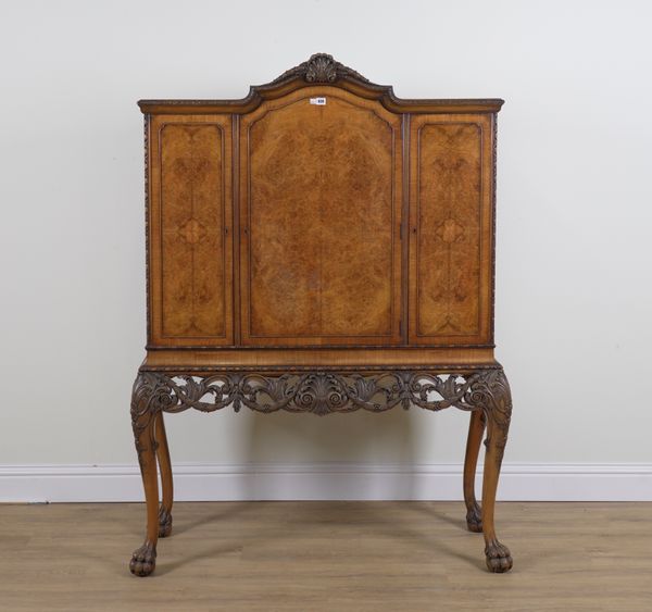 A MID 20TH CENTURY QUEEN ANNE STYLE FIGURED WALNUT THREE DOOR CABINET ON STAND