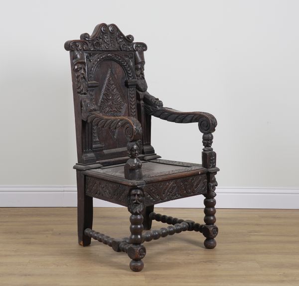 AN EXTENSIVLEY CARVED OAK OPEN ARM WAINSCOTT CHAIR