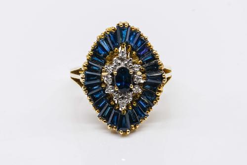 A GOLD, SAPPHIRE AND DIAMOND SHAPED OVAL CLUSTER RING