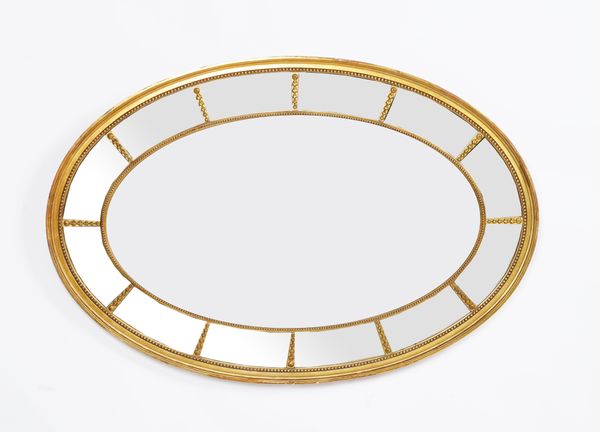 A REGENCY STYLE GILT FRAMED OVAL SECTIONAL WALL MIRROR