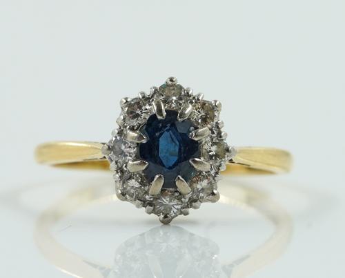 A GOLD AND PLATINUM, SAPPHIRE AND DIAMOND NINE STONE OVAL CLUSTER RING