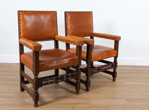 A PAIR OF CHARLES II STYLE OAK STUDDED TAN LEATHER UPHOLSTERED OPEN ARMCHAIRS (2)