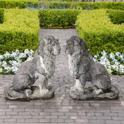 A PAIR OF PATINATED RECONSTITUTED STONE FIGURES OF SEATED LIONS