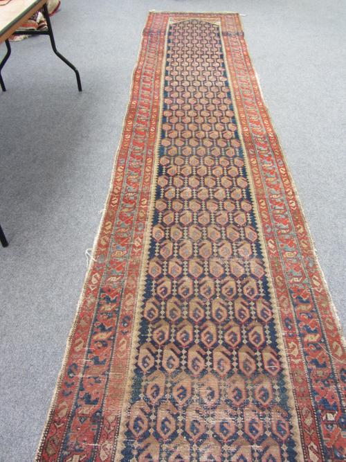 A Hamadan runner, Persian, the indigo field with rows of botehs, beige spandrels, a pale indigo and madder waved border, 530cm x 97cm.
