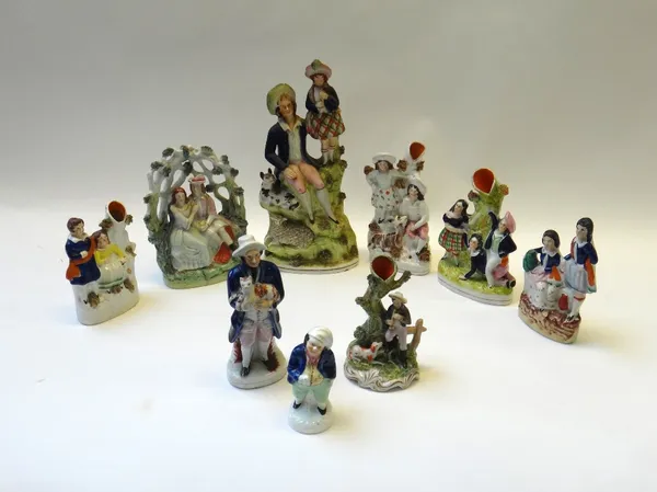 A group of nine Staffordshire figures and groups, 19th century, including four spill vases and a porcelain figure of a toper. (9)