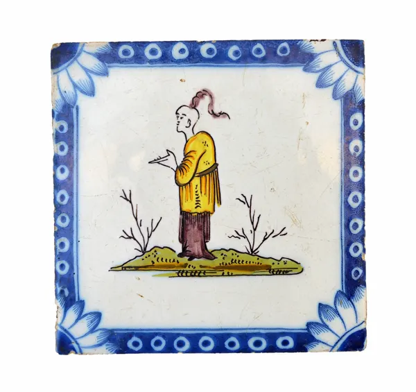 A Liverpool polychrome delftware tile, circa 1750-75, painted with an Oriental standing on grass inside a `Michaelmas daisy corner', 12.5cm.   Illustr