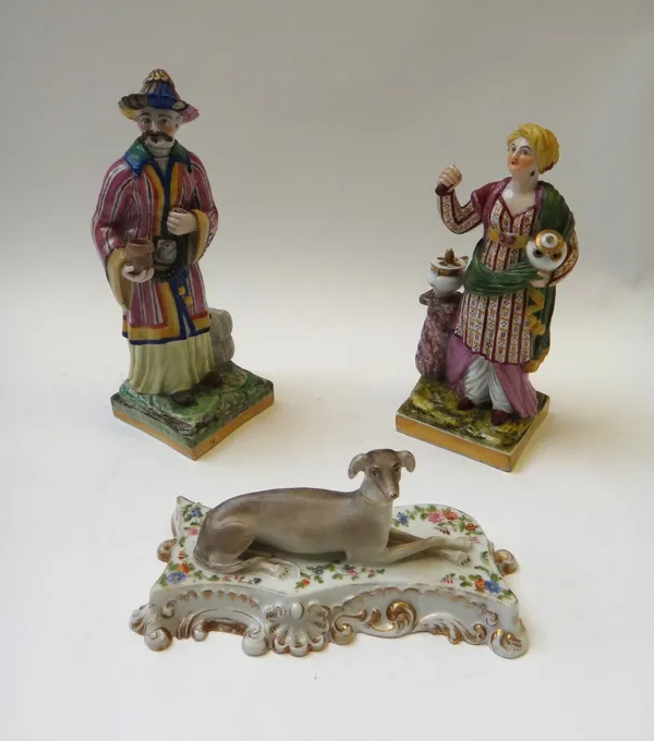 A Jacob Petit porcelain greyhound, mid 19th century, modelled atop a foliate decorated gilt shell scroll cushion, blue painted mark, 16cm wide, togeth