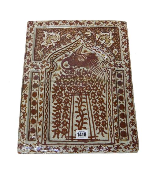 A large Kashan style copper lustre rectangular tile, probably 19th century, painted in the centre with a bird perched on top of a flowering tree, insi