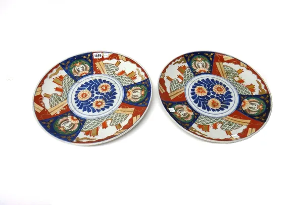 A pair of Japanese Imari dishes, Meji period, each painted with central flowers inside a panelled border, 38cm. diameter. (2)