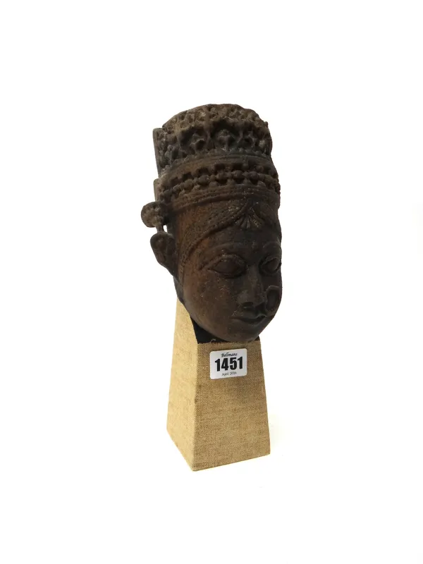 An Indian stone head of a deity, probably 18th century Gujaret, wearing a ring in her nose and a crown with hole in the top, probably part of a pilast