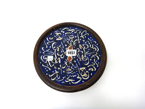A Kutahya calligraphic pottery tile, late 19th/20th century, of circular form, with white thuluth inscription against a deep blue ground, some letters