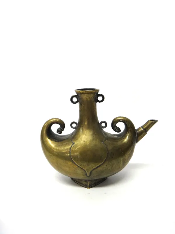 An Islamic bronze spouted vessel, probably late 19th century, with crescent shaped body and curled finials, the neck applied with four rings, 25cm. hi