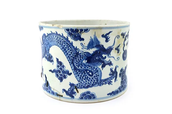 A Chinese blue and white cylindrical brushpot, Kangxi, painted with two confronting dragons chasing a flaming pearl amongst cloud scrolls (a.f), 14cm.
